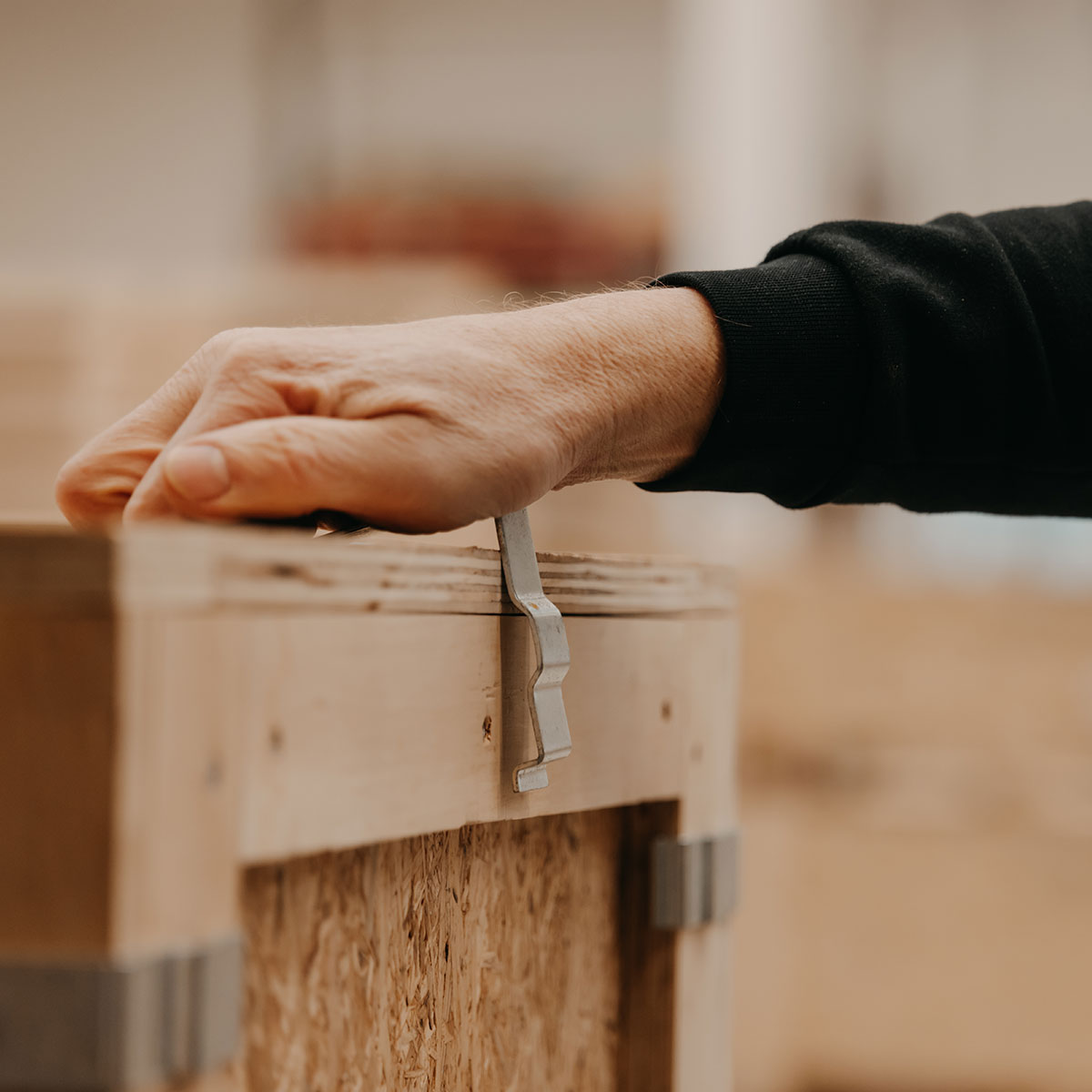 Hand schließt eine Klammer an einer Holz-Klammerkiste von BROPACK